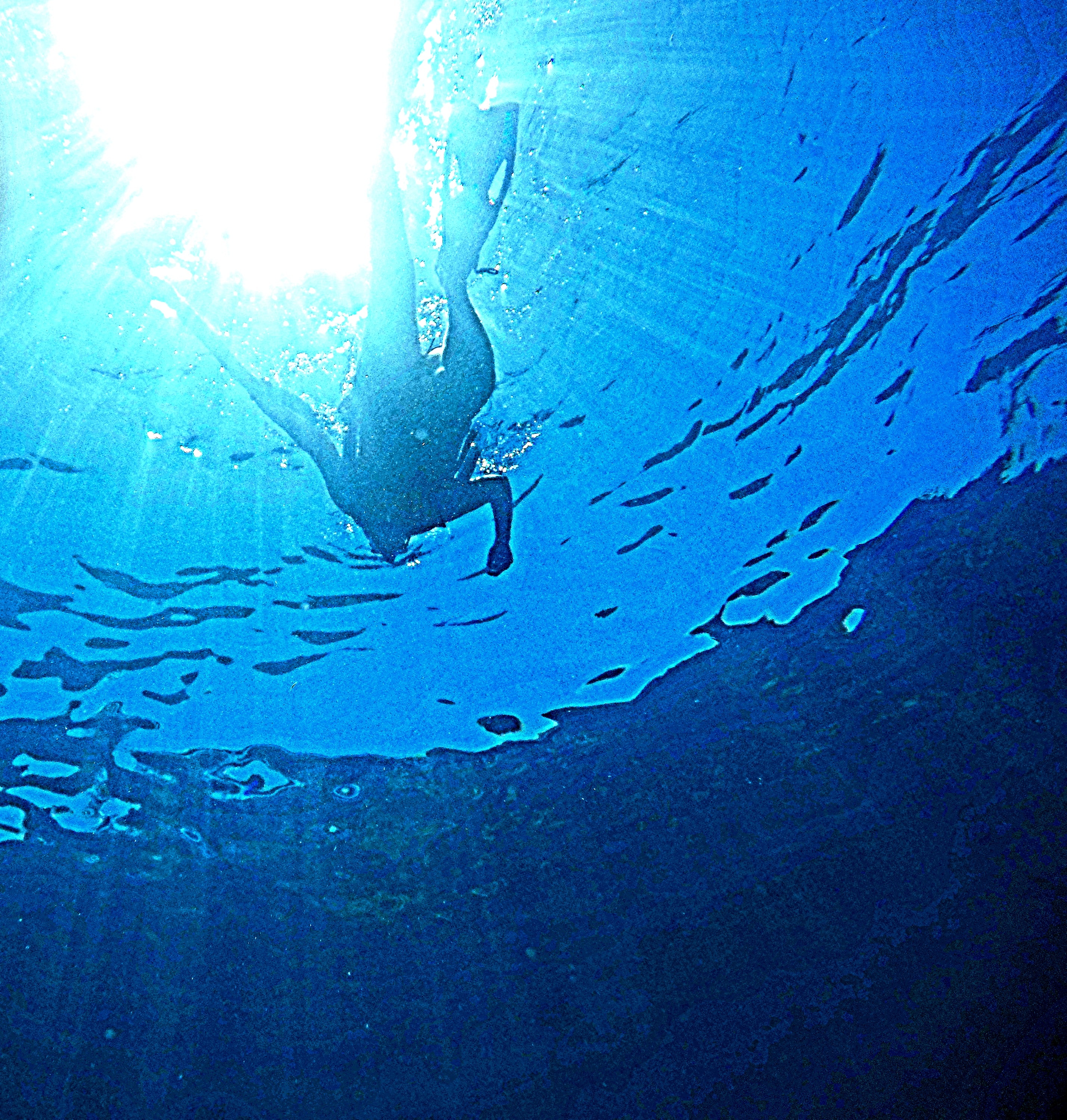 Diver silhouetted against brilliant sunburst from below the surface