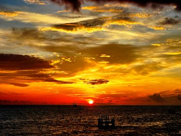 Dramatic sunset over ocean with silhouetted platform