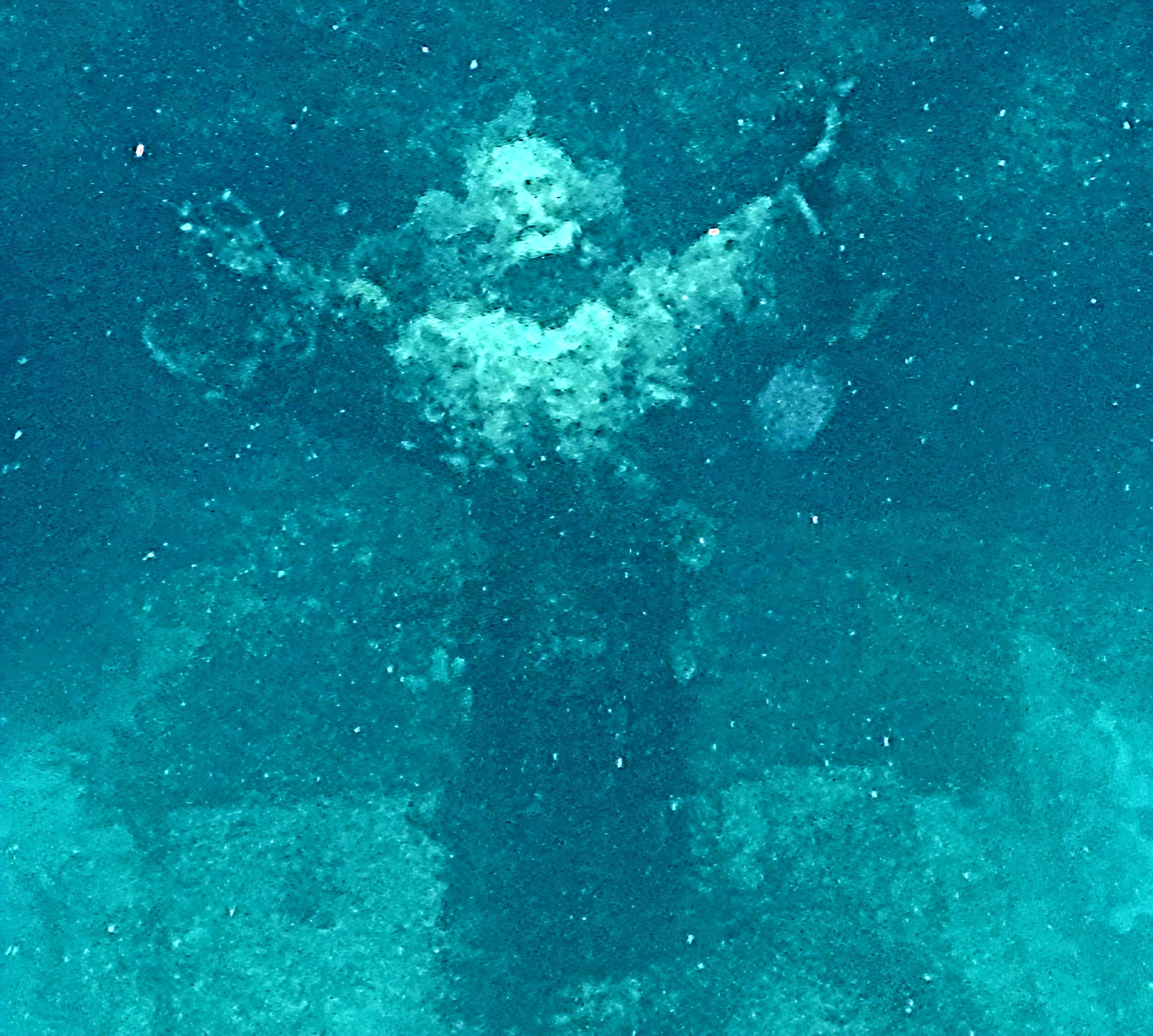 Underwater statue with arms outstretched on the ocean floor